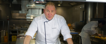 Chefkock beugt sich über Küchentisch Chef appuyé sur une table de cuisine